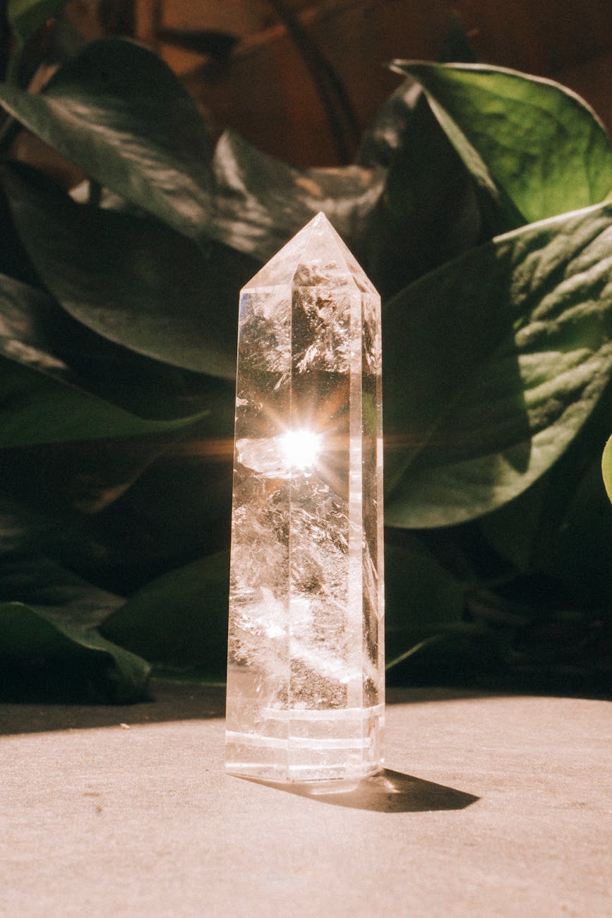 photo of the sun reflecting in a crystal and plant leaves in background